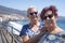 Couple of two female friends enjoying sea excursion  leaning against the railing of the seafront in a sunny day - wind, waves and