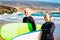 Couple of two happy and active seniors at the beach tryin to learn surfing - pensioners with surftables and wetsuits ready to