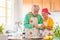 Couple of two happy seniors having fun and cooking together in the kitchen of their home - preparing some healthy food with