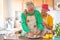 Couple of two happy seniors having fun and cooking together in the kitchen of their home - preparing some healthy food with