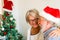 Couple of two old people pensioners having fun and laughing together at home with a christmas tree at the background and with the