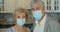 Couple of two seniors wearing medical mask to prevent coronavirus. Senior couple looking at the camera while wearing