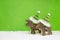 Couple of two wooden reindeer on green snowy christmas background.