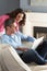 Couple Using Laptop Relaxing Sitting On Sofa