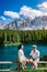Couple visit hte bleu lake in the dolomites Italy, Carezza lake Lago di Carezza, Karersee with Mount Latemar, Bolzano