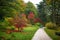 Couple walking along a path in a park, surrounded by foliage in vibrant autumnal hues