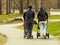 Couple Walking With Baby Strollers Through A Path In A Park