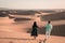 Couple walking at the beach of Maspalomas Gran Canaria Spain, men and woman at the sand dunes desert of Maspalomas