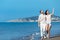 Couple walking on beach. Young happy interracial couple walking on beach smiling holding around each other.