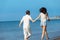 Couple walking on beach. Young happy interracial couple walking on beach smiling holding around each other.