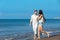 Couple walking on beach. Young happy interracial couple walking on beach smiling holding around each other.