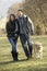 Couple walking golden retriever in the country