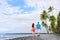 Couple walking on Hawaii secluded black sand volcanic beach on the Big island of Hawaii, hawaiian destination tropical