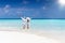 Couple walks down a tropical beach in white clothing