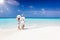 Couple walks hugging down a tropical beach during their vacation