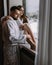 Couple wearing bathrobes in hotel standing near window