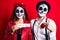 Couple wearing day of the dead costume holding trick or treat paper pointing finger to one self smiling happy and proud