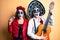 Couple wearing day of the dead costume playing classical guitar using microphone afraid and shocked with surprise and amazed