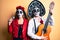 Couple wearing day of the dead costume playing classical guitar using microphone making fish face with mouth and squinting eyes,