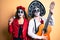 Couple wearing day of the dead costume playing classical guitar using microphone puffing cheeks with funny face