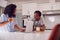 Couple Wearing Pyjamas Standing In Kitchen Working From Home On Laptop