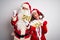 Couple wearing Santa costume holding wow and sale banner over isolated white background very happy and excited doing winner