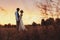 Couple in wedding attire against the backdrop of the field at sunset, the bride and groom.