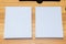 A couple of the white colored hardcover books laying out on the top of a table with wooden texture and some decorations arranged