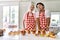 Couple of wife and husband cooking pastries at the kitchen sticking tongue out happy with funny expression