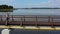 Couple of wife and husband walking on wooden bridge. Fisherman boats on lake