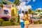 Couple on winter vacation taking pictures of pastel colored beach houses cottages in tropical holiday destination Fort