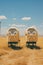 A couple of yellow train cars sitting on top of a dry grass covered field. Generative AI image.