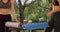 Couple of yoga girls sitting at table with mats and drinks in park in England