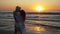 Couple of young man and woman meeting on a sandy beach and kissing at sunrise