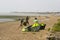 A couple of young men struggle against a stiff breeze to prepare their para glider for an afternoons sport at the beach