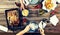 Couple of young people at the dinner table with a variety of foods, baked chicken legs, potatoes barbecue, beer, pickles and snack