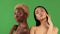 Couple of young sexy girls they are posing in studio with bare shoulders on isolated green background. Concept of female