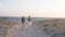 Couple of young women walking sandy beach at the dusk Indie boho style Swimwear and shorts