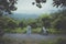 couples of biker pulling small enduro motorcycle on country track among rain falling