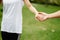 Couples holding hands in front of green grass