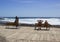 Couples relaxing on a wooden viewing deck at the beach on a hot sunny day in Playa Las Americas in Teneriffe in the Spanish Canary