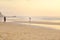 Couples walking on beach at sunset.