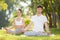 Couples Yoga, man and woman doing yoga exercises, meditate in the park. Yoga outdoor. Concept of healthy lifestyle and relaxation