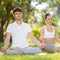 Couples Yoga, man and woman doing yoga exercises, meditate in the park. Yoga outdoor. Concept of healthy lifestyle and relaxation