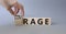 Courage and rage symbol. Businessman hand turnes wooden cubes and changes word Rage to Courage. Beautiful grey background.