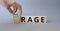 Courage and rage symbol. Businessman hand turnes wooden cubes and changes word Rage to Courage. Beautiful grey background.