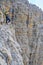 Courageous female climber looking down from high up on via ferrata Cesare Piazzetta, Dolomites mountains, Italy. Summer adventure