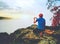 Courageous man sitting on the peak of rock makes phone photo