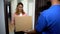 Courier giving cardboard box to woman signing delivery order, internet shop