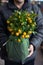 Courier holds packaged gift of decorative small fruit-bearing tangerine tree at the greek garden shop in February before delivery